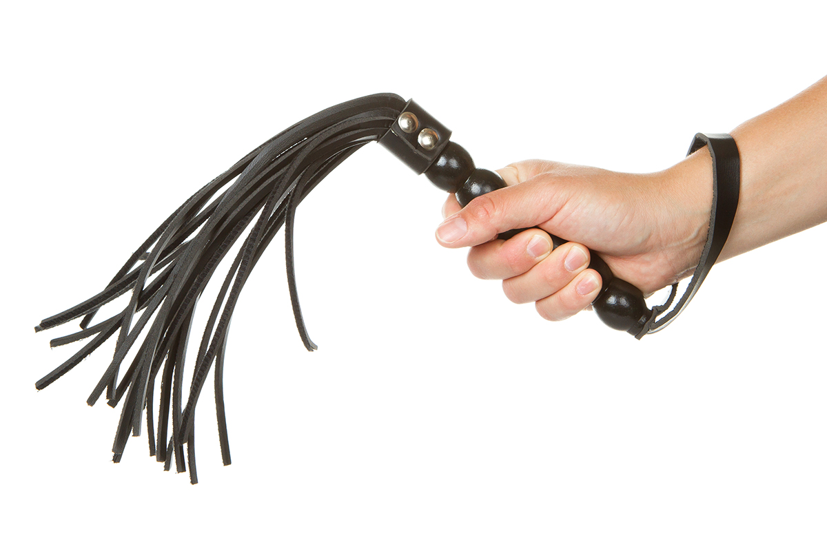 Strict Black Leather Flogging Whip in woman's hand isolated over white background